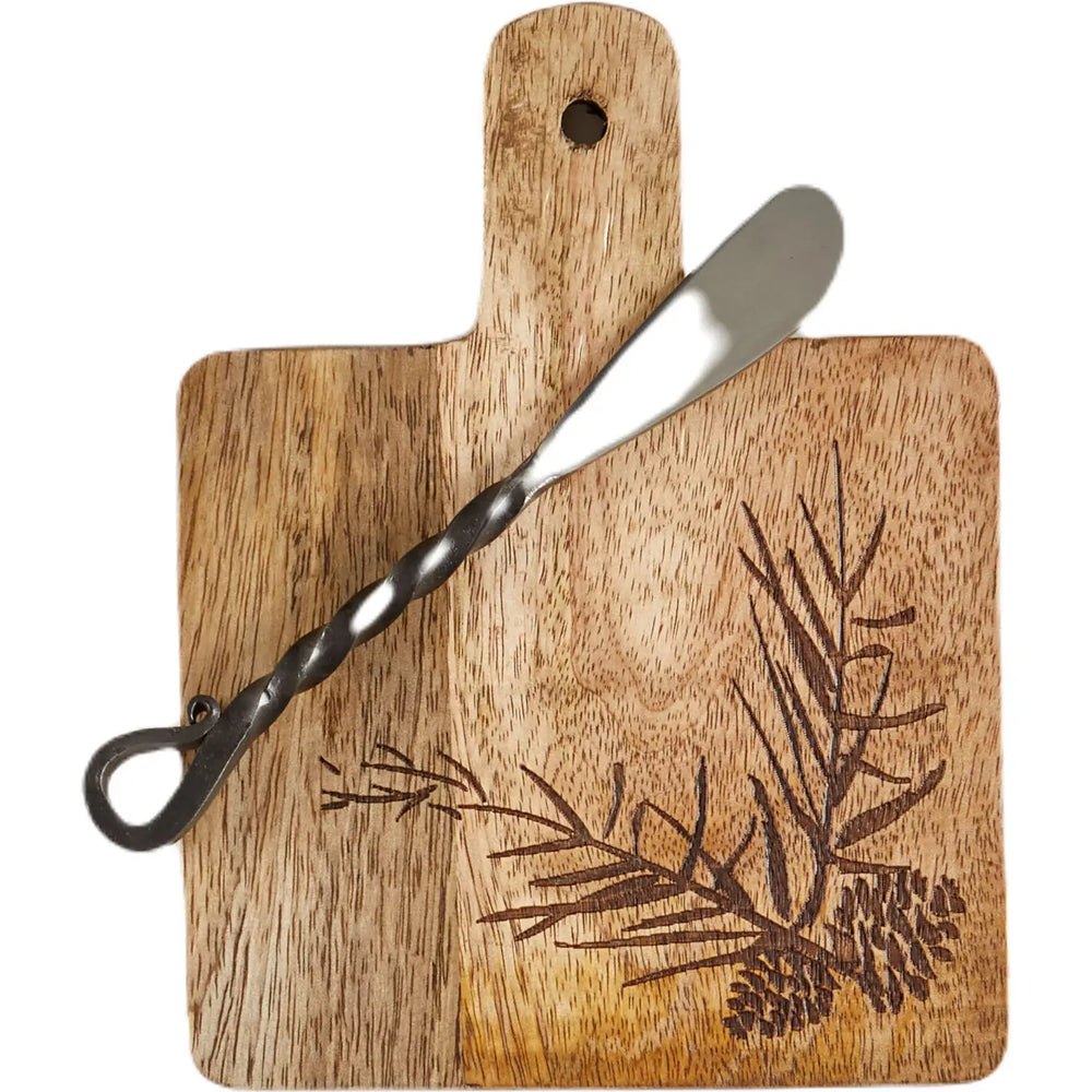 Round wooden serving board with a handle and engraved leaf pattern, shown with a metal spatula on a white background.