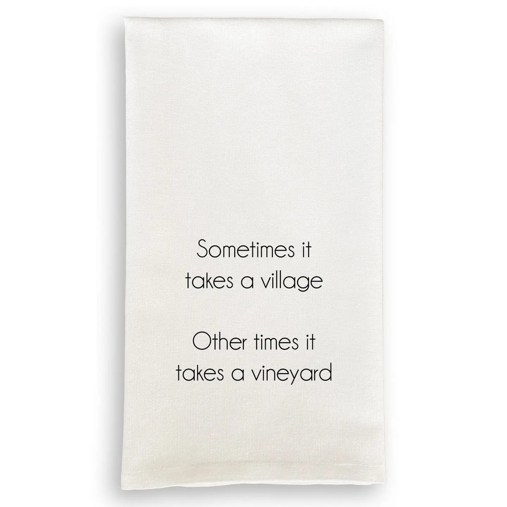 White cotton tea towel with black text reading "Sometimes it takes a village. Other times it takes a vineyard."