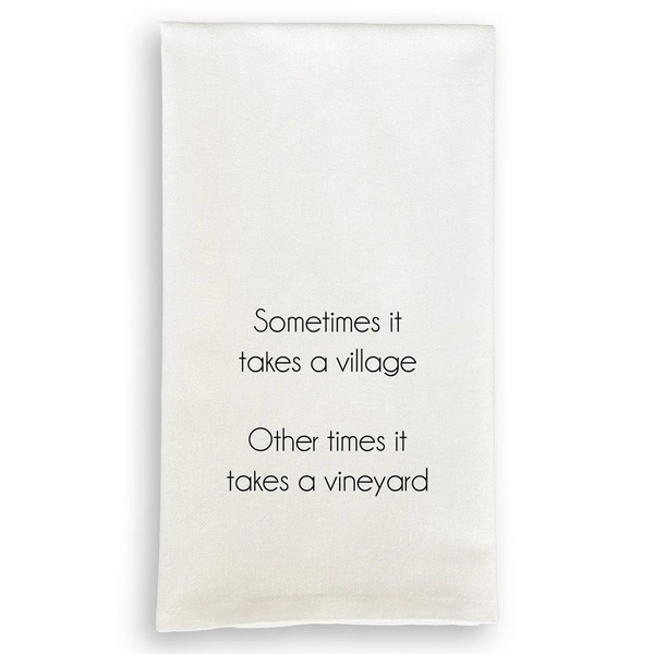 White cotton tea towel with black text reading "Sometimes it takes a village. Other times it takes a vineyard."