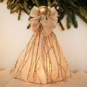 Handmade sinamay angel tree topper with a glittered cone-shaped gown and wings, gold twigs, and a gold halo, glowing softly from a flameless candle inside.