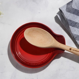 Red Le Creuset pot with a wooden spoon on a light gray surface