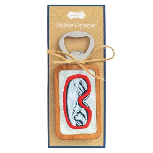 A wooden bottle opener with a red and white embroidered goggle design, presented on its kraft paper backing card tied with twine.