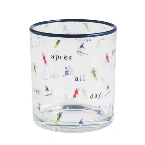 A clear glass tumbler with a dark navy rim, decorated with a pattern of colorful skiers and the words 'après', 'all', and 'day' in black.