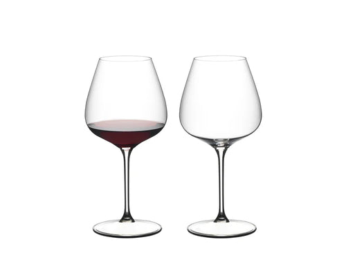 Two clear stemmed wine glasses on a white background, with the left glass partially filled with red wine and the right glass empty.