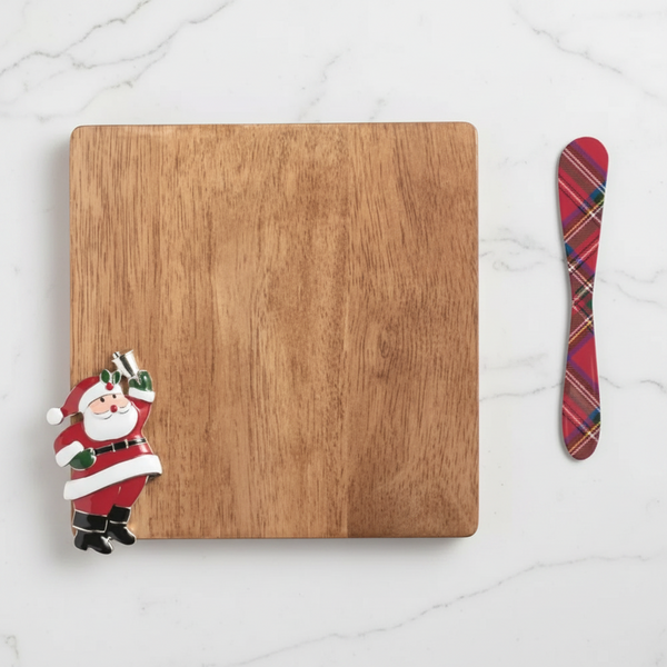 A square wooden serving board with a Christmas-themed design, featuring a Santa Claus figure on the bottom-left corner and a red tartan-patterned spreader on the right side, set against a plain white background.