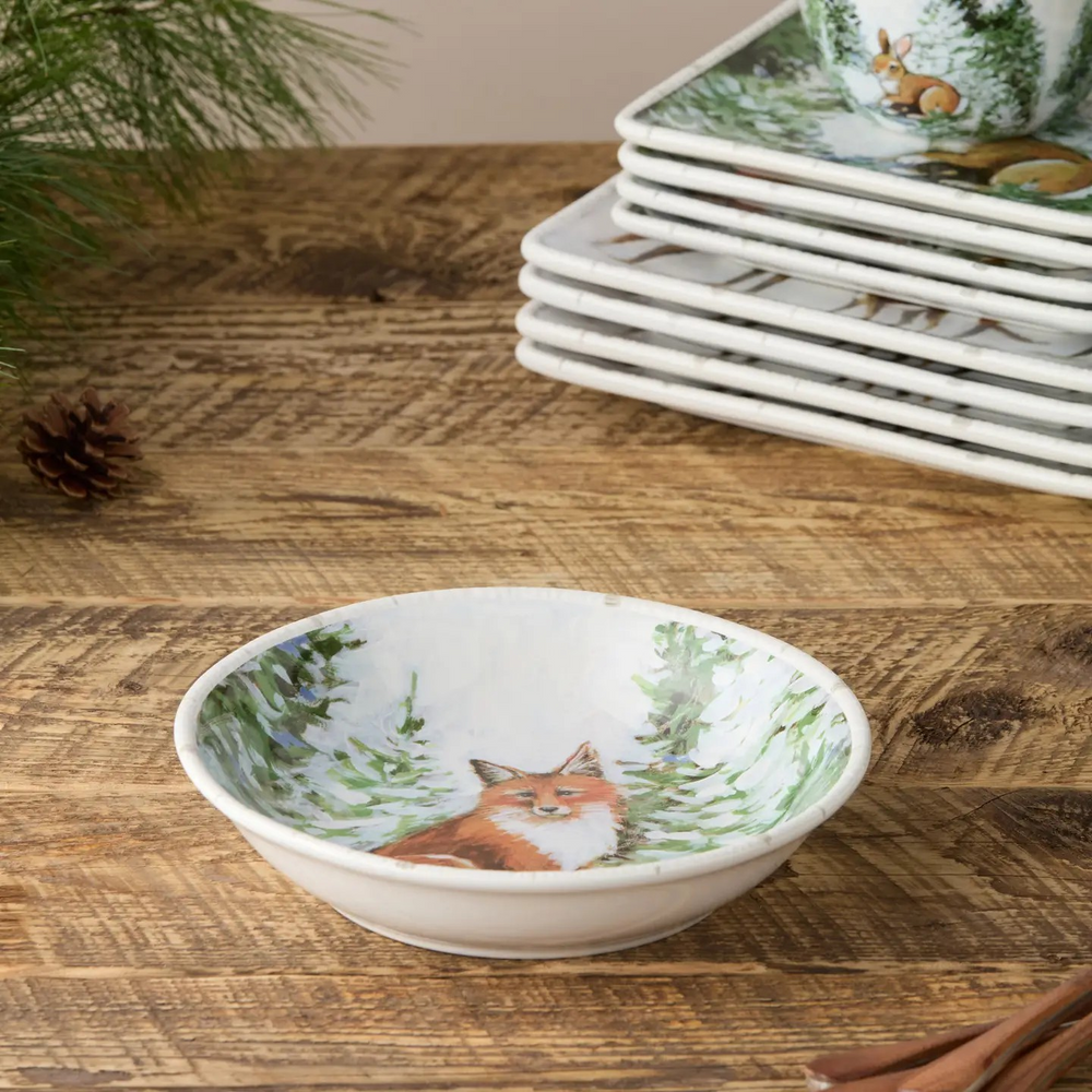 Wide porcelain soup bowl with a painted winter scene of snowy evergreens and woodland wildlife.