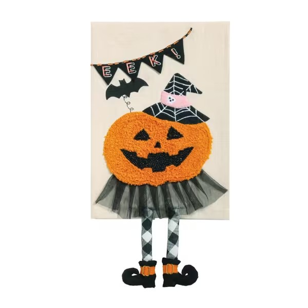 A Halloween-themed decorative wall hanging featuring a large orange jack-o'-lantern face with black stitched details, a black witch hat with spiderweb pattern, a black tutu skirt, and legs in black-and-white argyle with black shoes. Above the figure is a black banner with triangular flags spelling 'HAPPY' and a small black bat, all mounted on a cream rectangular panel against a white background.