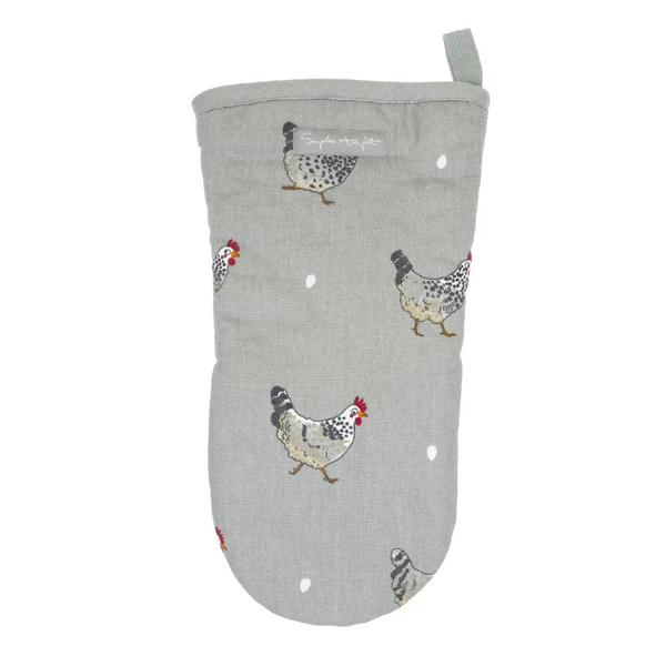 A single oven mitt in a muted sage green color, printed with a pattern of black-and-white speckled chickens and small white dots, laid flat on a white marble surface.