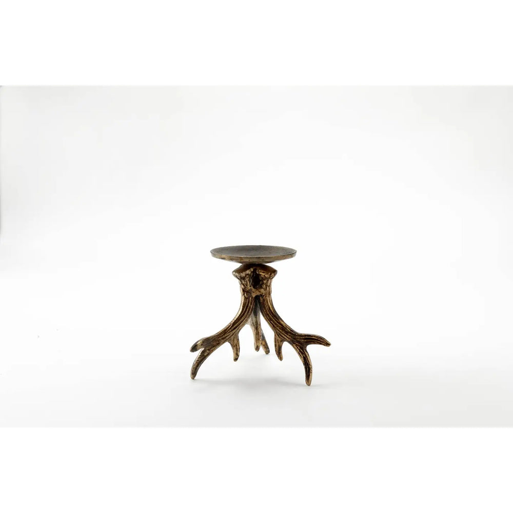 A cream-colored pillar candle displayed on a rustic, antler-like bronze metal holder against a clean white studio background.