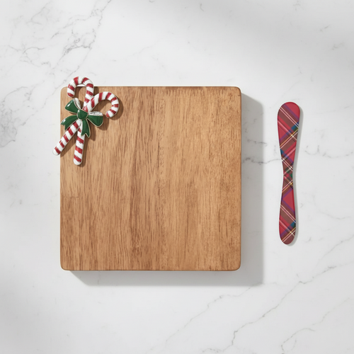Wooden cutting board with candy cane decorations and a plaid spreader on a white background