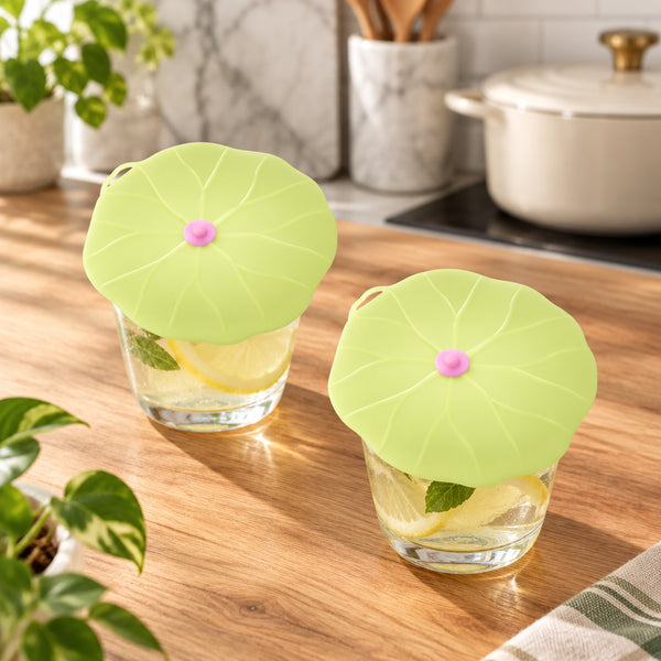 Two pale yellow-green lotus-shaped silicone ear plugs with small pink centers, shown on a plain white background.