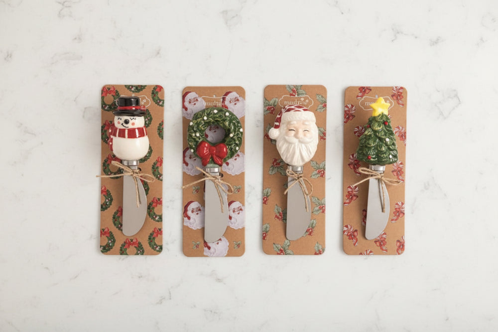 Four Christmas-themed decorative spreader handles mounted on tan patterned cards against a white background. The designs include a snowman, a wreath with a red bow, Santa Claus, and a Christmas tree with a yellow star.