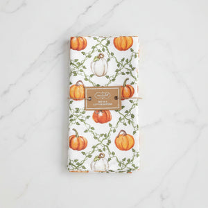 A set of 4 white cotton napkins featuring a watercolor autumn pumpkin pattern with green vines, tied together with a twine bundle and a brown paper label.