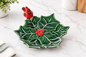 Holly leaf-shaped ceramic plate with a red cardinal perched on green holly leaves and upturned leaf corners.