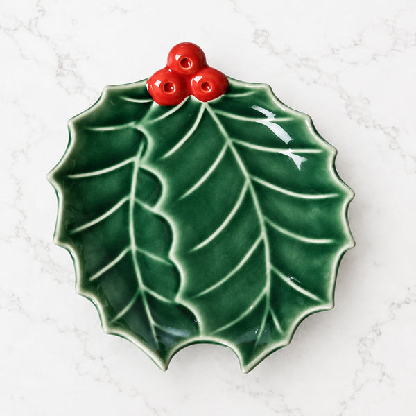 Holly-shaped ceramic plate with green leaves and bright red berries.