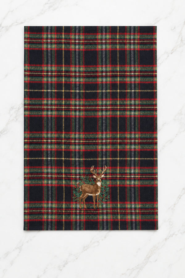Black plaid woven kitchen towel with green, red, and yellow accents and an embroidered deer surrounded by holly leaves and red berries.