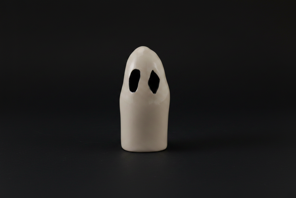 White ghost-shaped object with black eyes on a white background
