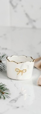 Aspen Kitchens Home+Gift stoneware Christmas tidbit bowl with a white finish, gold bow motif, and scalloped gold edge.
