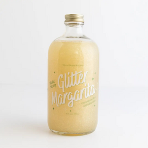 Bottle of glitter margarita with a gold cap on a white background