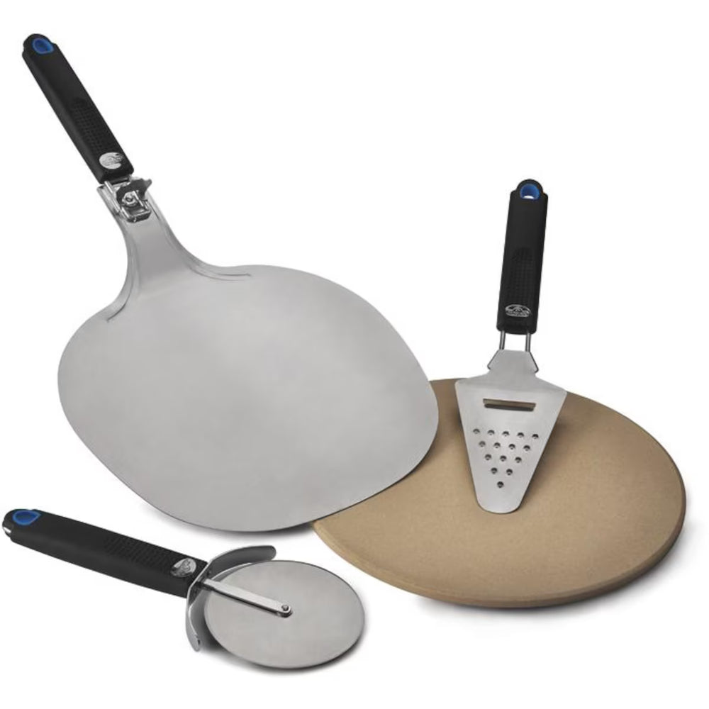 Outdoor pizza serving set on a dark woven patio table, featuring a wooden pizza board with a whole and sliced pizza, a pizza cutter, a cheese server, plates, and a small dipping dish. A wicker chair and patio background are visible.