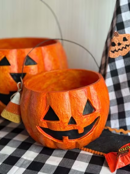 Halloween-themed paper lanterns with jack-o'-lantern faces on a checkered tablecloth.