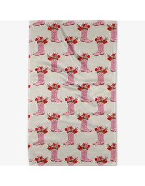 A rectangular fabric item, likely a tea towel or kitchen towel, featuring a repeating pattern of pink cowboy boots filled with red roses on a light beige background.