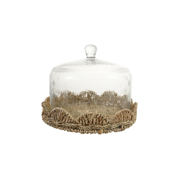 A clear glass cloche dome with a textured pattern and a small white knob, resting on a natural beige woven jute base against a solid white background.