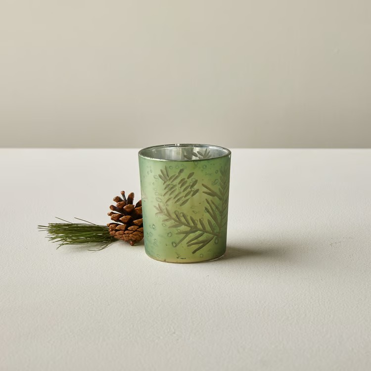 Gold glass votive candle holder etched with a pinecone and pine branch, with a mirrored silver interior.