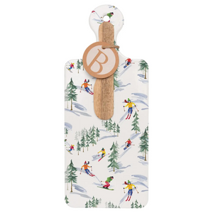 Rectangular ceramic serving board decorated with skiers on a snowy slope, with a mango wood spreader tucked into the handle.