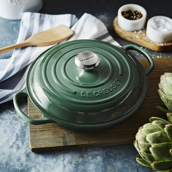 Le Creuset Braiser in the color artichaut on a wood cutting board