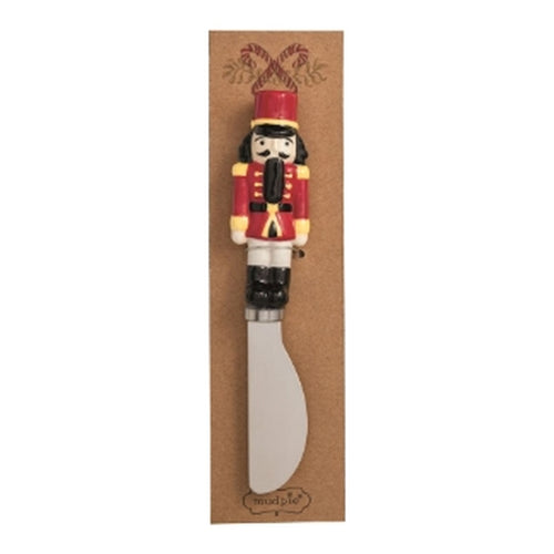 Stainless steel spreader with a hand-painted red nutcracker soldier handle on a kraft gift card.
