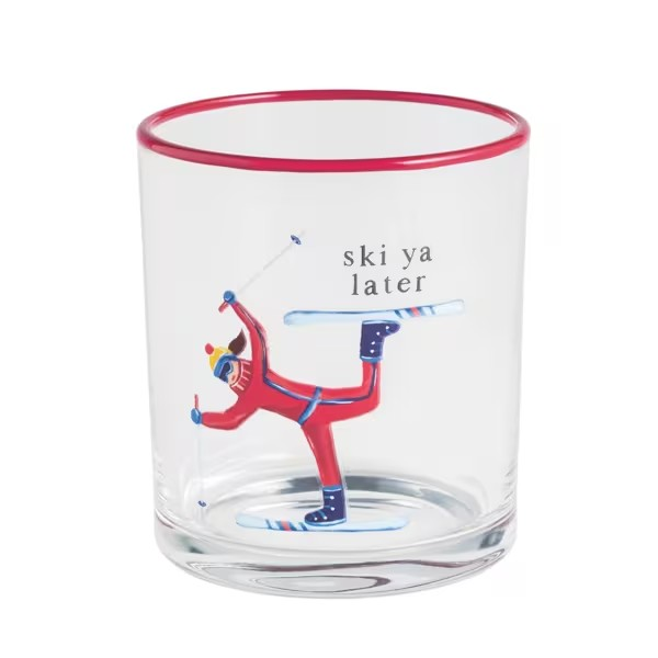 A clear glass tumbler with a red rim, featuring a printed illustration of a skier in a red suit performing a trick with the text 'ski ya later' on a white background.