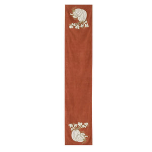 A long, narrow terracotta-colored runner or table runner with embroidered autumn motifs, including pumpkins and white flowers, shown on a plain white background.