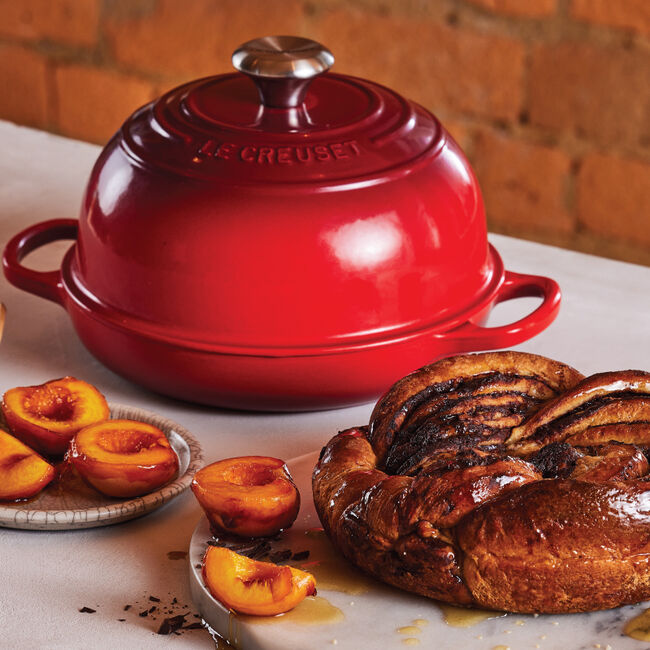 Le Creuset Cerise Bread Oven with some glazed peaches and a loaf