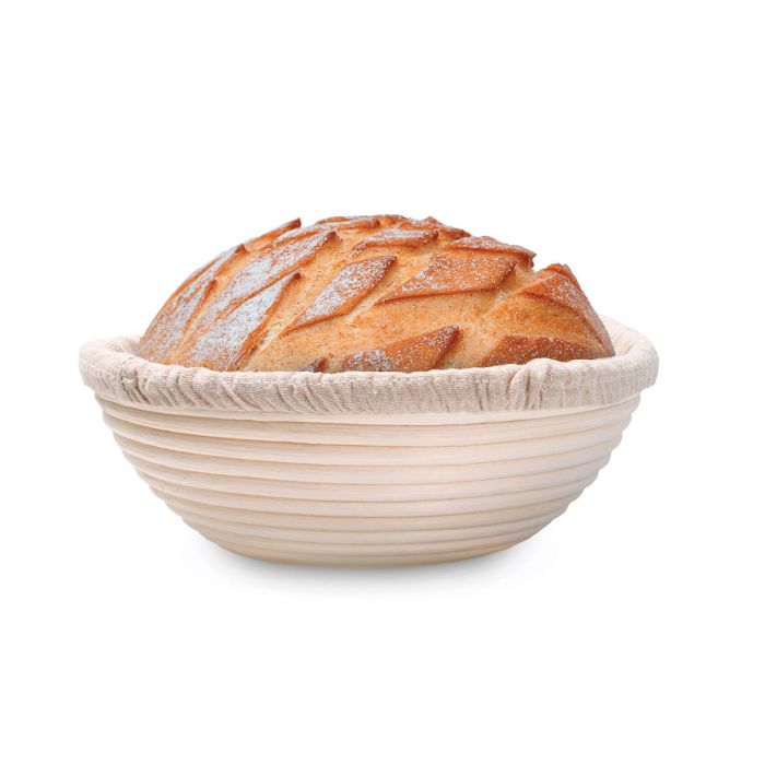 Loaf of bread in a banneton basket on a white background
