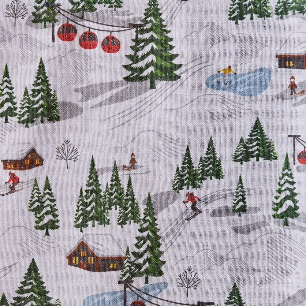 White cotton placemat with an allover ski village print of skiers, red gondolas, log cabins, ice skaters, and snowy evergreen trees.