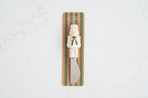 A small knife with a cream-colored handle shaped like a nutcracker, mounted on a striped cardboard backing with the brand name 'Intrudle' visible at the top.