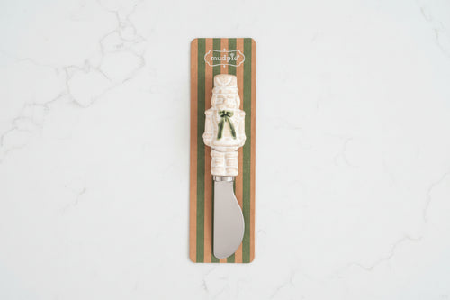A small knife with a cream-colored handle shaped like a nutcracker, mounted on a striped cardboard backing with the brand name 'Intrudle' visible at the top.
