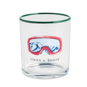 A clear glass tumbler with a green rim, featuring a graphic of red ski goggles with a blue mountain view and the text 'views & booze' printed below.