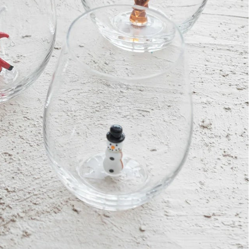 Set of clear wine glasses with small decorative figures on a light wooden surface