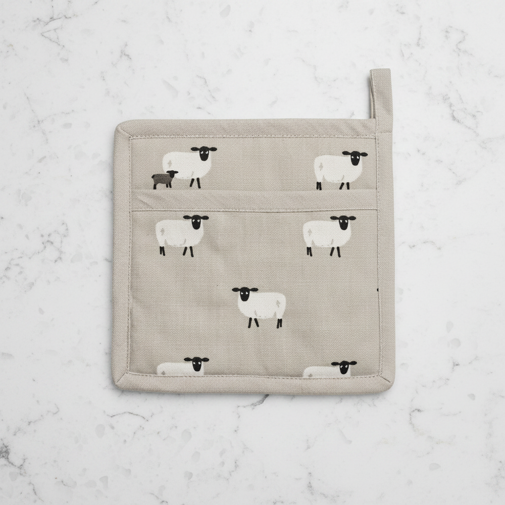 A square beige fabric pot holder featuring a repeating pattern of white sheep, with a top loop handle and a small side tag.